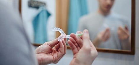 Man applying whitening gel in front of mirror
